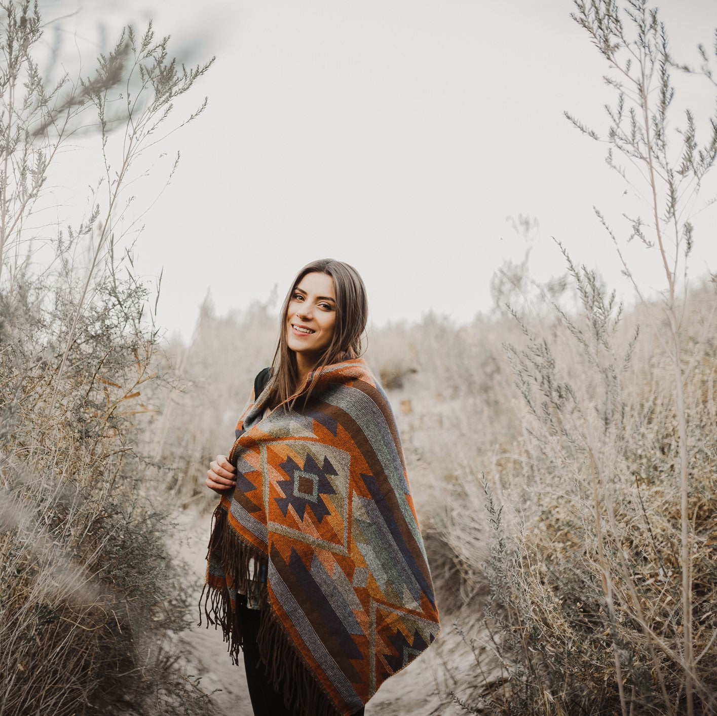 Frau mit Poncho in herbstlicher Landschaft
