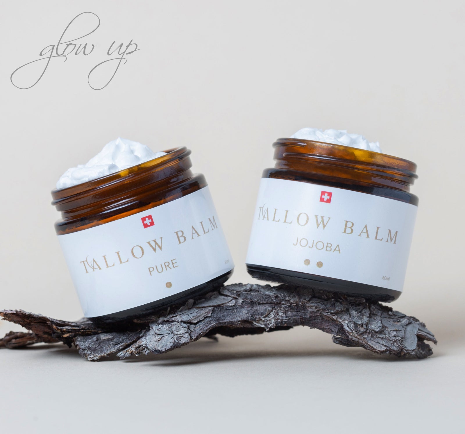 Zwei Swiss Tallow Balms dekorativ nebeneinander auf Baumrinde arrangiert