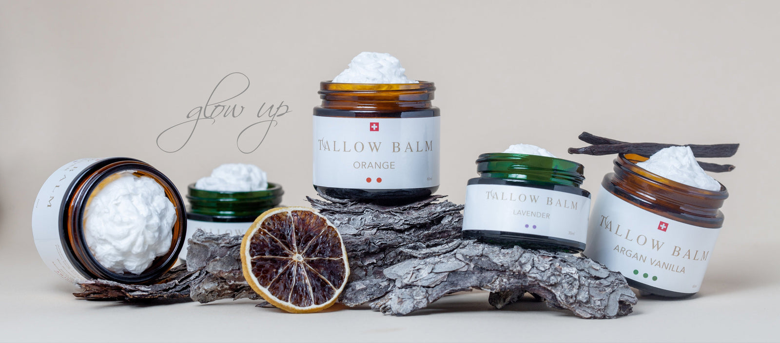 Verschiedene Swiss Tallow Balms dekorativ nebeneinander auf Baumrinde mit Naturdeko