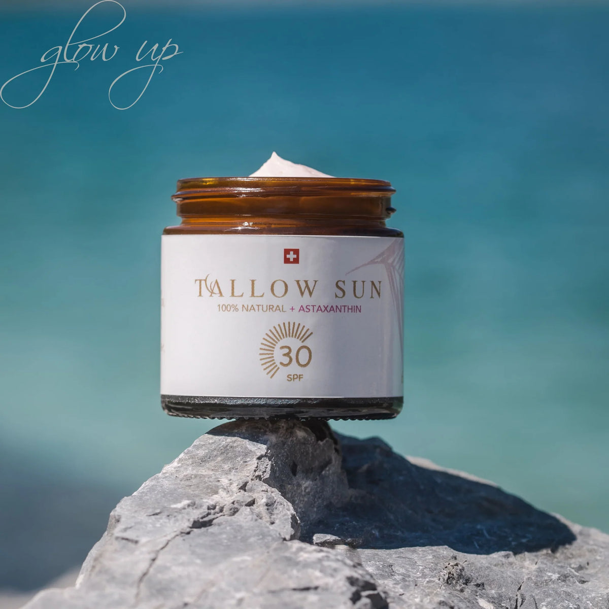 Swiss Tallow Sun Sonnencreme mit SPF 30 auf Fels vor türkisblauem Wasser, mit cremiger Textur unter freiem Himmel