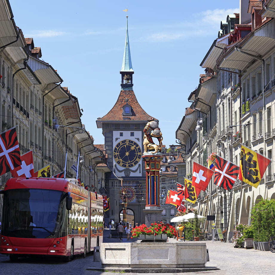 Zytglogge in der Altstadt von Bern mit Schweizer Flaggen und Sommerstimmung